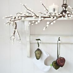 a white shelf with ornaments hanging from it's sides and a candle in the background