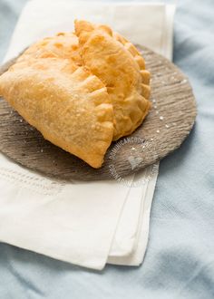 two pastries sitting on top of a wooden plate next to a white cloth napkin