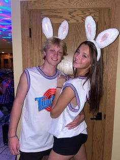 two people in bunny ears standing next to each other with their arms around one another