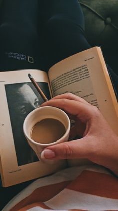 a person holding a cup of coffee and an open book