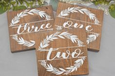 three wooden signs with the words, two one and two on them sitting next to flowers