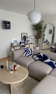 a living room filled with furniture next to a wooden table and white wall mounted clock