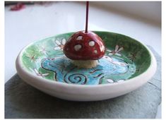 a small mushroom sitting on top of a green and white plate with a toothpick sticking out of it