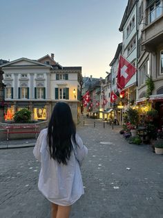 a woman walking down a street next to tall buildings