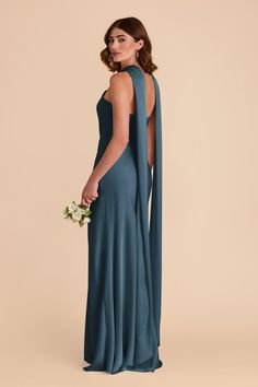 a woman in a long blue dress with an open back, holding a flower bouquet