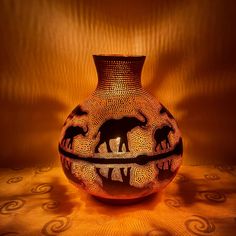 a vase with elephants painted on it is lit by a light from the lamp shade