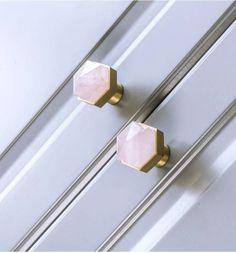 two knobs on the side of a white door with gold trim and pink glass