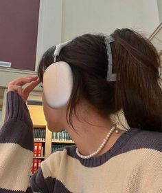 a woman with headphones on her ears looking at books in a library while she is listening to music