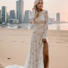 a woman standing on top of a sandy beach next to the ocean wearing a white dress