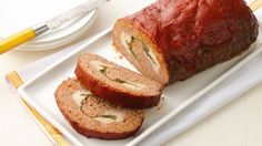 sliced meatloaf sitting on a white plate next to a knife and fork,