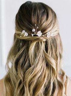 a woman with long blonde hair wearing a white flowered hair comb in her hair