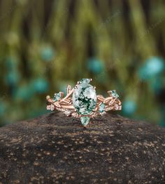 a ring with green and white stones sitting on top of a rock