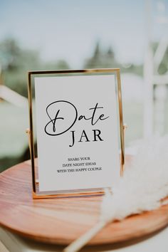 a sign that says date jar sitting on top of a wooden table next to a white feather