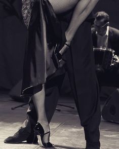 a man and woman dance on stage in black and white attire with their legs crossed