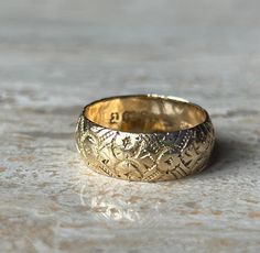 a close up of a gold wedding ring on a marble surface with no one around it