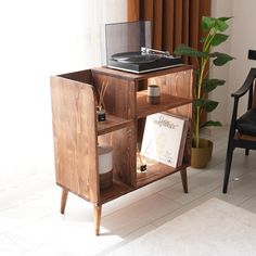 a record player sitting on top of a wooden cabinet next to a potted plant