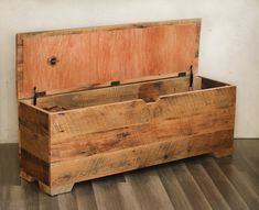 an old wooden box sitting on top of a hard wood floor next to a wall