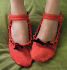 a close up of a person wearing red slippers with bows on the toes and feet