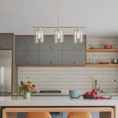 two stools sit in front of a kitchen island with three lights hanging over it