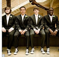 a group of young men sitting next to each other in front of a statue wearing suits