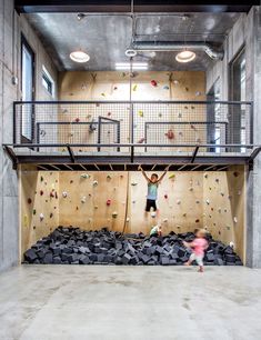 a person climbing up the side of a wall in a room filled with black rocks