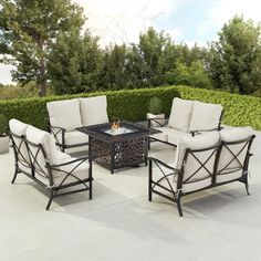 the patio furniture is set up outside on the concrete flooring area with bushes in the background