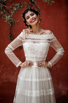 a woman in a white dress standing with her hands on her hips and smiling at the camera