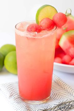 a watermelon and limeade drink in a tall glass next to a bowl of fruit