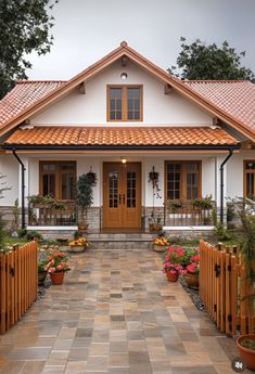 a white house with red tile roof and wooden fence