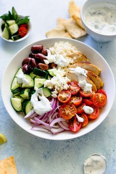 a white bowl filled with vegetables and pita chips on top of a blue table