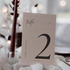 the table numbers are placed on top of napkins and place cards in front of candles