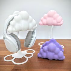 two cloud shaped headphones sitting on top of a wooden table next to each other