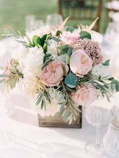 a vase filled with lots of flowers sitting on top of a white table cloth covered table