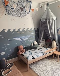 a child's bedroom decorated in blue and white with an ocean theme on the wall