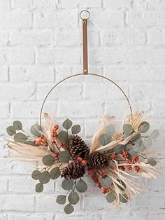 a white brick wall with a wreath and pine cones hanging from it