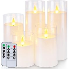 four lit candles with remote controls in front of each one on a white background,