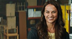 a woman is smiling and standing in front of shelves