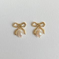 Decorate yourself with these Brass Bow beauties with two freshwater pearl drops with a shimmery golden 18CT Gold Plating. Inspired by a love of Victorian bygone jewels, these earrings are a playful nod towards popular motifs used, it's all about the dangle, brining a little glamour to your ears to be enjoyed on any occasion. .All posts are made from sterling silver and coated in 18CT Gold to protect sensitive ears All pieces are handmade to order please allow 2-3 weeks for delivery. Your earrin Earrings With Pearls, Wire Jewellery, Preppy Jewelry, Smink Inspiration, Jewelry Accessories Ideas, Dope Jewelry, Jewelry Essentials, Classy Jewelry, Jewelry Lookbook