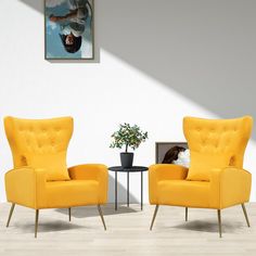 two yellow chairs sitting next to each other in front of a painting on the wall