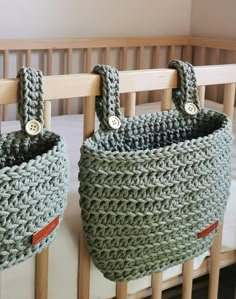 two crocheted baskets hanging on the side of a wooden rail in a baby's room