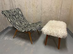 two zebra print chairs sitting next to each other on top of a cement floor in front of a wall