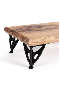 a wooden table with black metal legs on a white background in front of a white backdrop