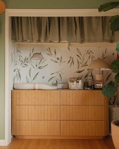 a wooden dresser sitting next to a plant in a room