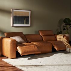 a brown leather couch sitting in a living room next to a painting on the wall