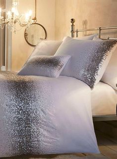 a bed with silver sequins on it and a chandelier in the background