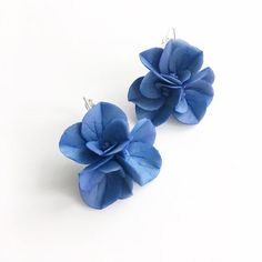 two blue flower earrings sitting on top of each other