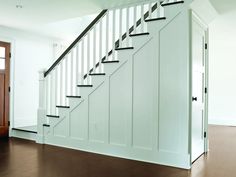 an empty room with a stair case next to a wooden door and brown flooring