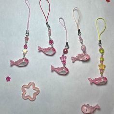 five different necklaces are shown on a white surface with pink and yellow charms hanging from them