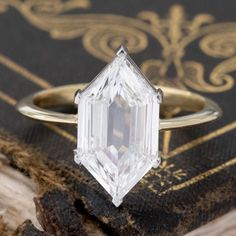 a close up of a diamond ring on top of a book with an old book in the background