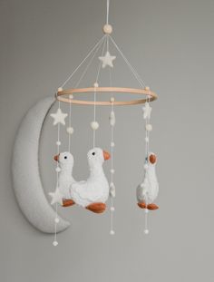 a mobile with three ducks hanging from it's sides and the moon in the background